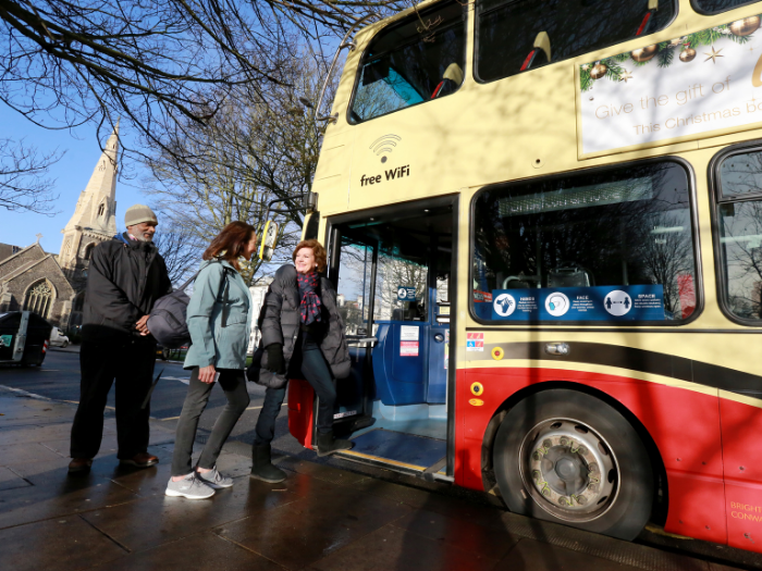 "Three people queuing to get onto a bus"