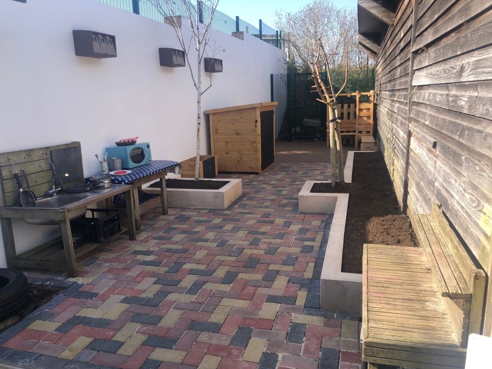 "side garden at Acorn nursery with mud kitchen and trees planten in beds "