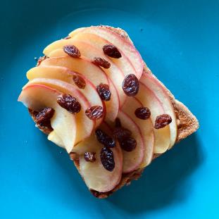 "Some slices apple and sultanas on half a piece of wholemeal toast"