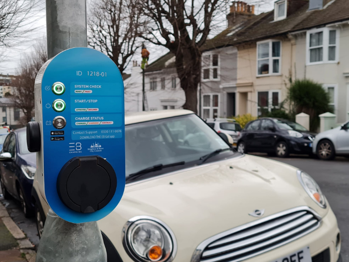 "a road with a parked car with an electric vehicle lamppost charger"