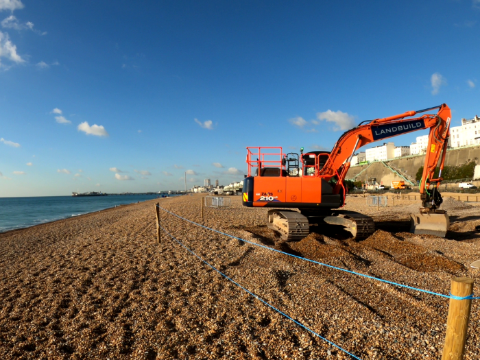 "A picture of a bulldozer picking up shingle on a beach"