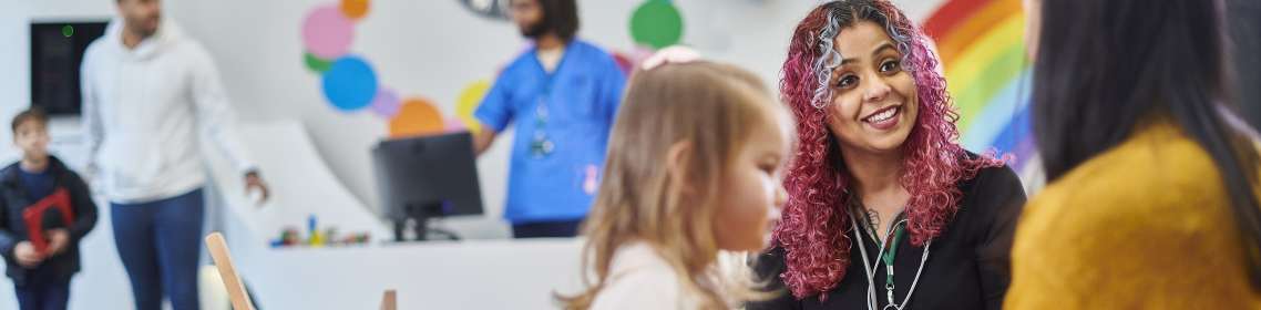 Health workers talking to adults and children in a reception area