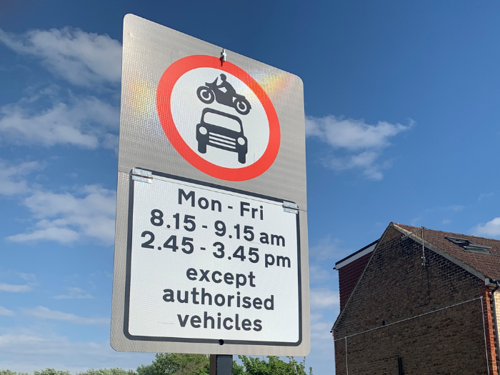 A picture of a road sign with houses in the background