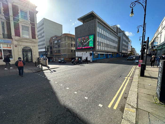 a road, pavement, buildings and blue sky