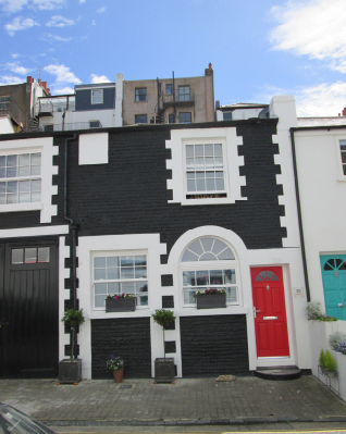 Two storey flint cobble building with painted brick dressings and a red front door.
