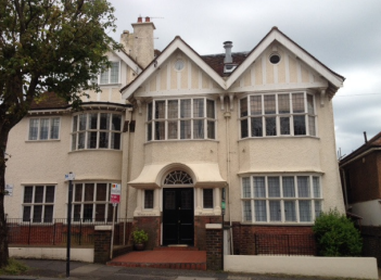 A large 3 storey cream house with white wooden eaves