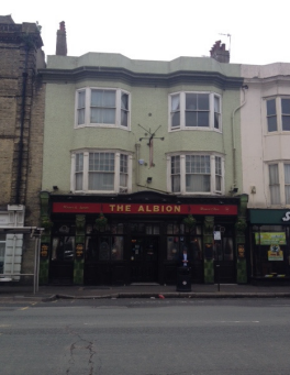 The Albion pub, A lime green builing with a dark green tiled ground floor frontage. This is the pub entrance. There is a band of red between the ground and first floors, on it the pub's name is embossed in gold