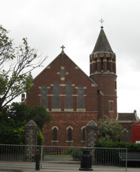 A large redbrick church with a circular tower rising from it.