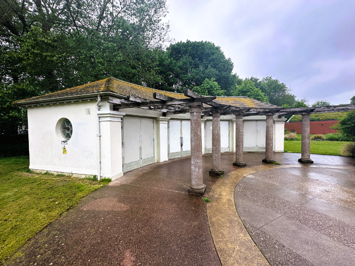A picture of a white building with paving, grass and trees