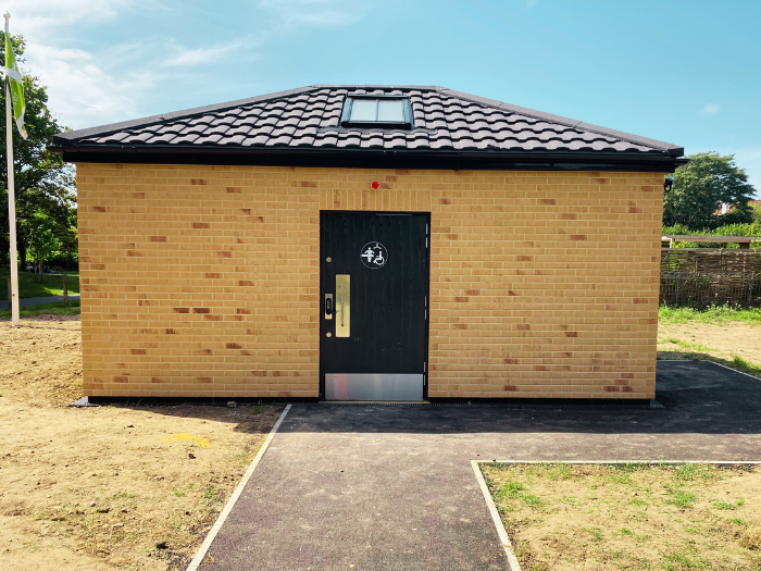A picture of a toilet block with a path leading to it and grass around it