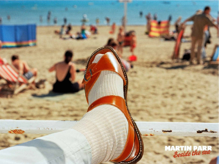 A picture of a foot in a sock and sandal on the beach