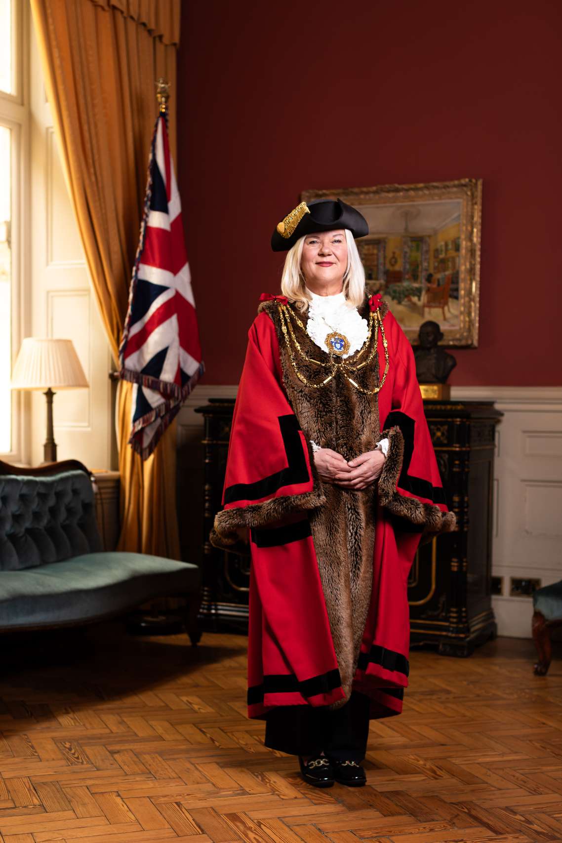 The image shows an official portrait of new Mayor of Brighton & Hove, Councillor Amanda Grimshaw, wearing Mayoral robes in Mayor's parlour in front of the union flag.