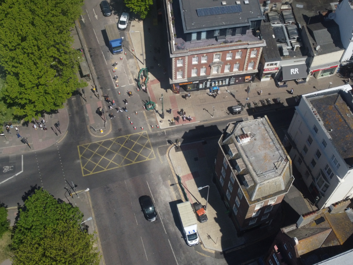 A drone shot of a road junction with cars and trees