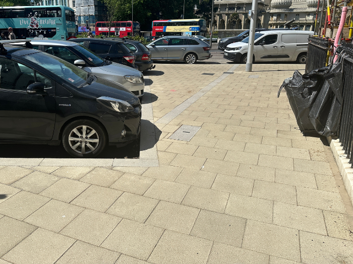 A picture of a pavement with cars parked 