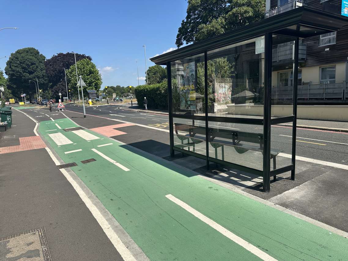 A picture of a bus stop next to a cycle lane