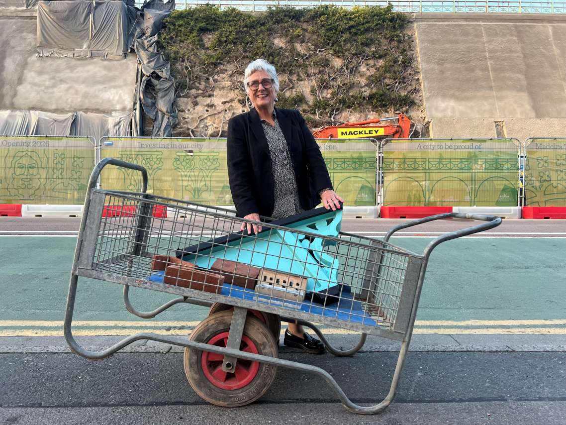 Councillor Julie Cattell with a trolley holding a piece of restored cast iron and bricks in front of the Madeira Terrace restoration site