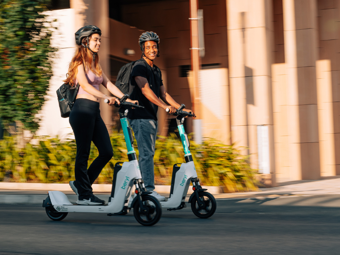two people riding electric scooters