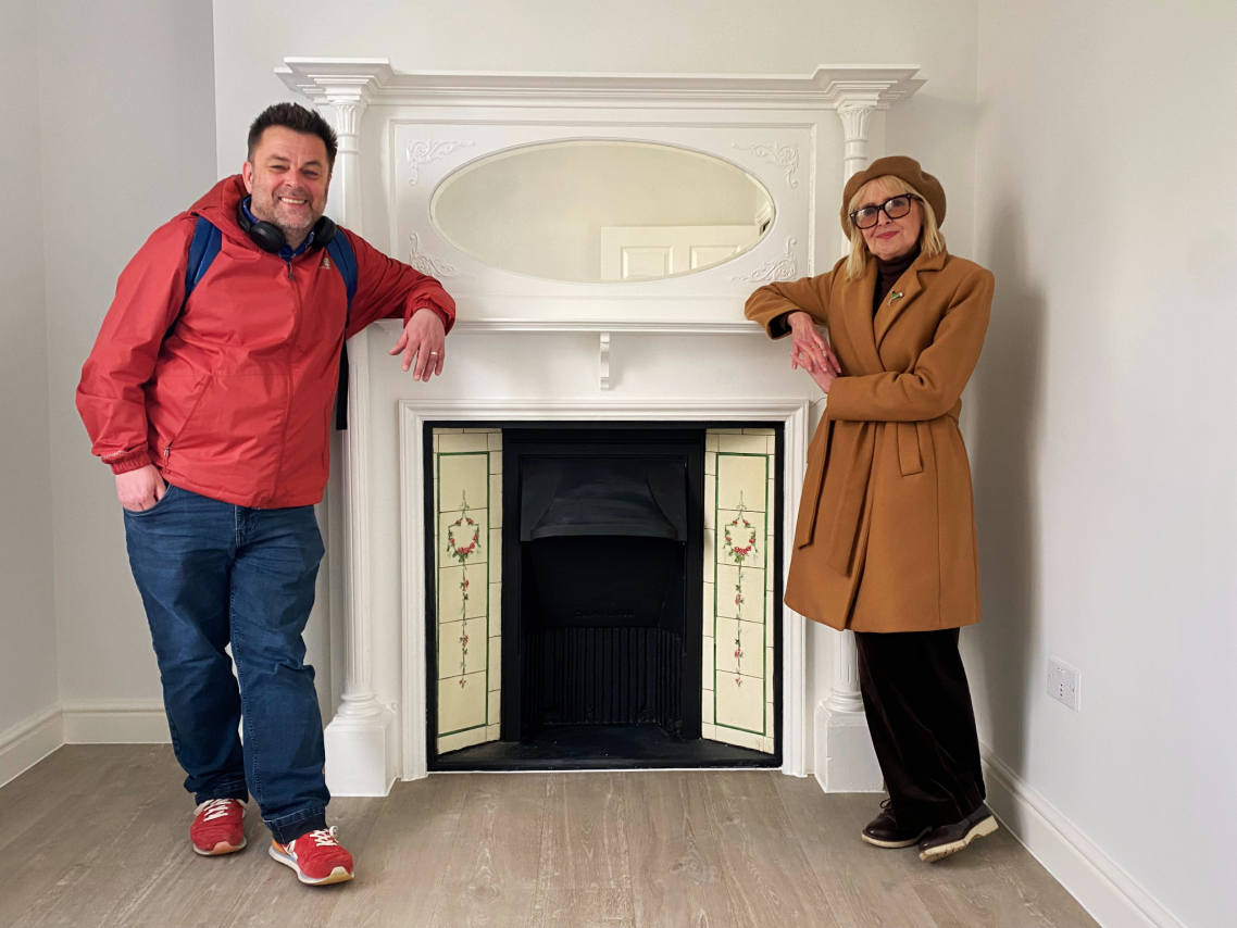 Cllr Gill Williams and Cllr Paul Nann standing together at an ornate fireplace.