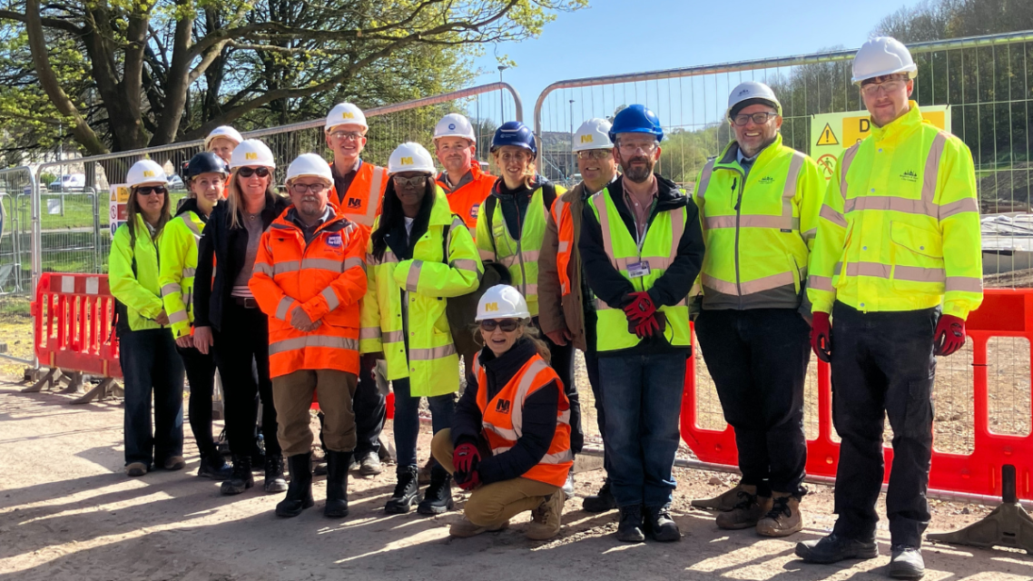 The rainscape project team. A group of people. All of them are wearing hard hats. Some are wearing hi-vis jackets, and others are wearing hi-vis vests.