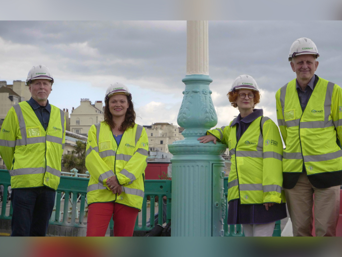 4 people standing either side of a streetlighting column