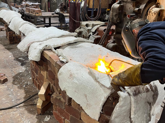 a person with a blowtorch working on a streetlight column