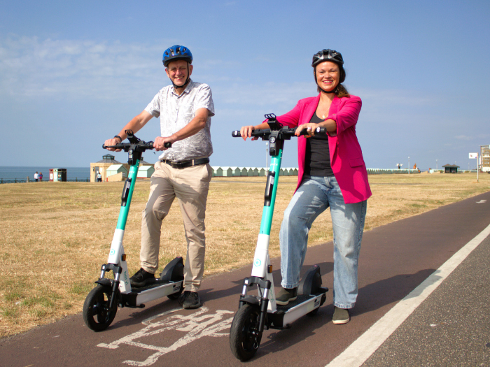 two people posing on e-scooters