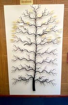 Bronze memorial tree against white background. Several leaves across the branches.