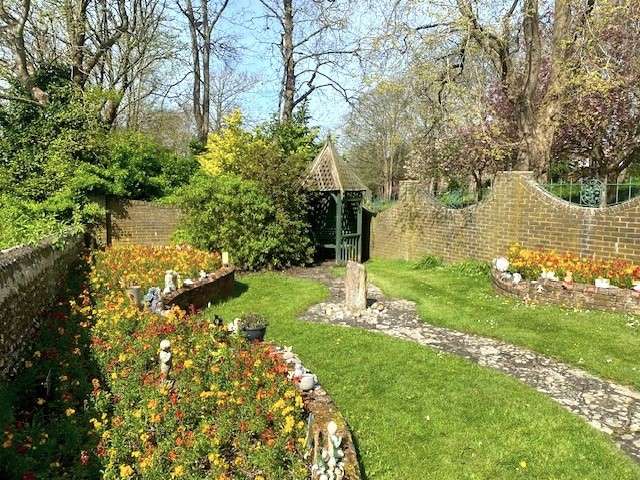Children's memorial garden. Small shelter at end of garden, with green lawns and flower beds either side.