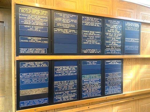 Blue panels on wall with memorial text on them in gold.