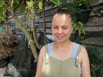 Carmen standing in front of a wooden wall and a tree