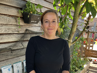 Francesca standing in front of a wooden wall and tree.