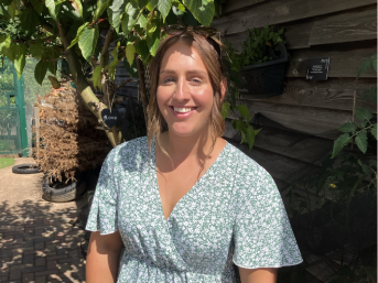 Georgia Trigwell standing in front of a tree and wooden background.