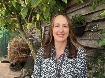 Wendy standing in front of wooden wall and tree