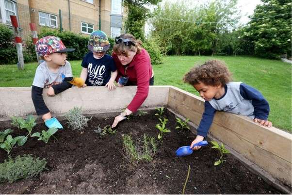 Children and nursery worker gardening.
