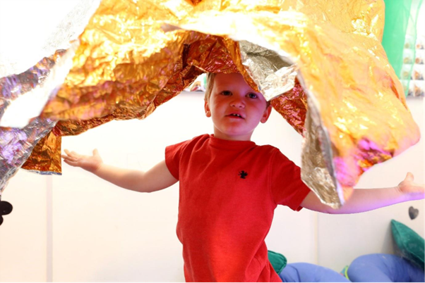 Child in a nursery playing with colourful material.
