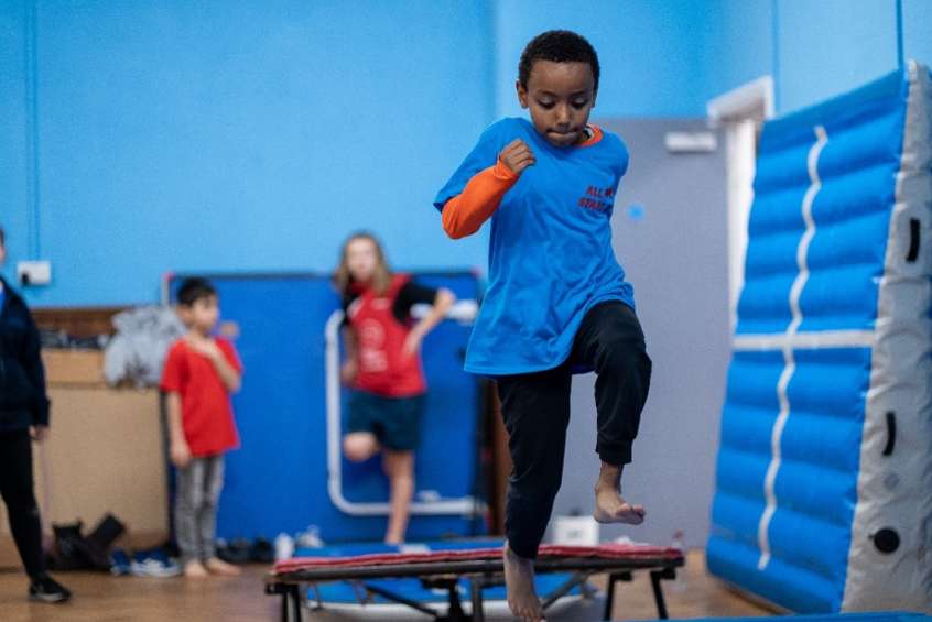 Young boy jumping in the air in a sports hall.