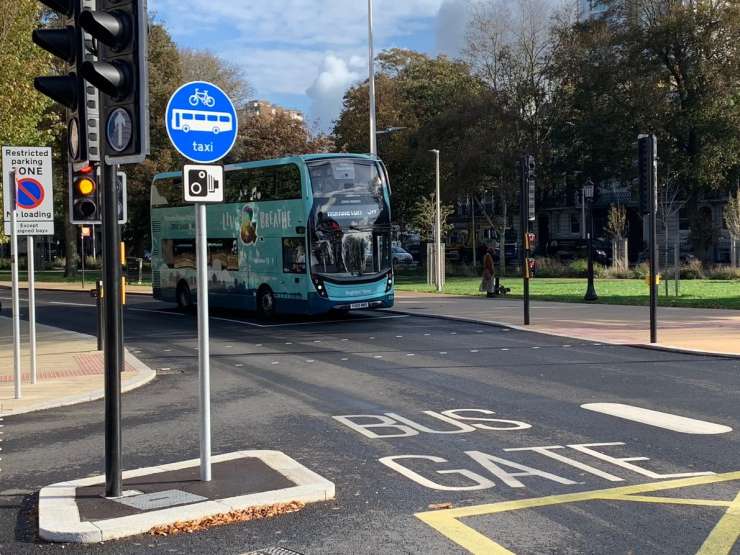 A bus on a road with a blue sign and the words &lsquo;Bus gate&rsquo; painted on the road