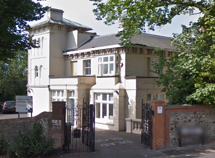The building from the junction of Dyke Road and Clifton Terrace with boundary wall and gates in the foreground.