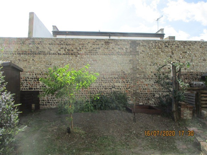The tall flint wall taken from rear gardens.