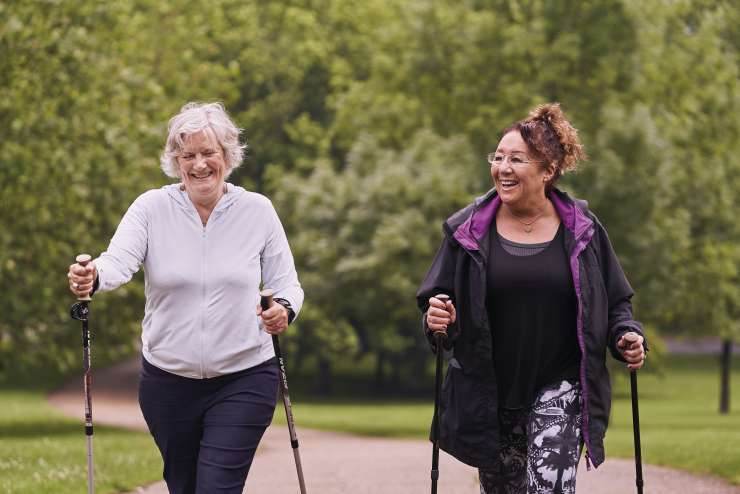 Two women walk together using hiking poles