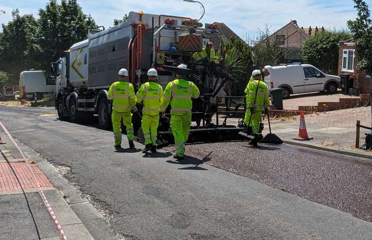A truck with a group of workers putting micro asphalt on the road.