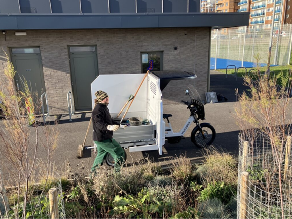 A council worker taking large tools out of an E-Cargo bike parked up alongside a building.
