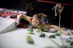 Woman climbing up an indoor rock wall.