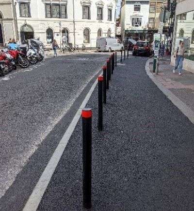 A widened pavement with temporary plastic bollards separating the road from the pavement.