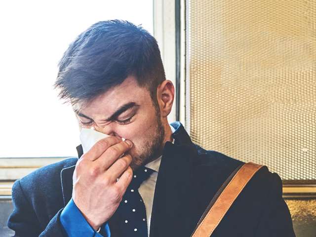 Man sneezing with a tissue