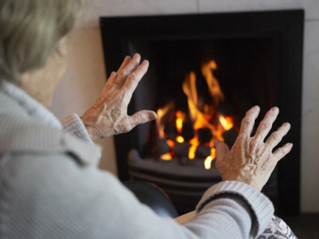Back of a woman warming her hands in front of a fire