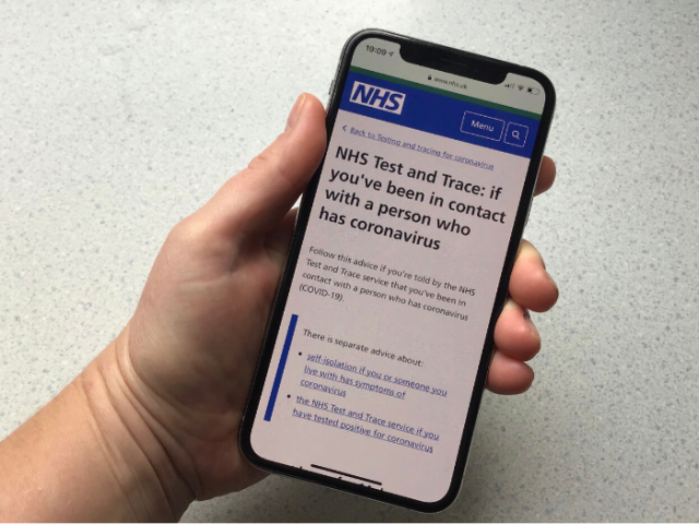 Photo of a hand holding a mobile phone showing the NHS  Test and Trace website