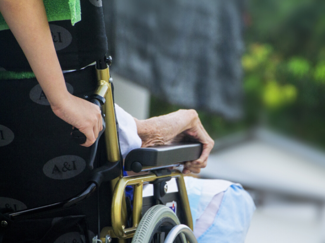 Photo of someone's hands pushing someone in a wheelchair
