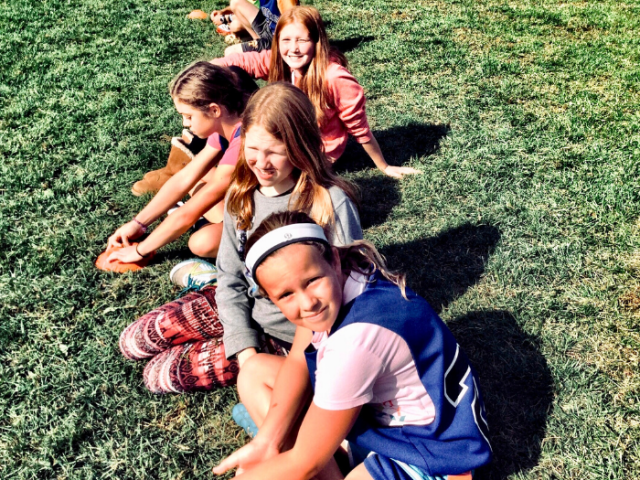 Group of children between 7 and 10 sitting on some grass