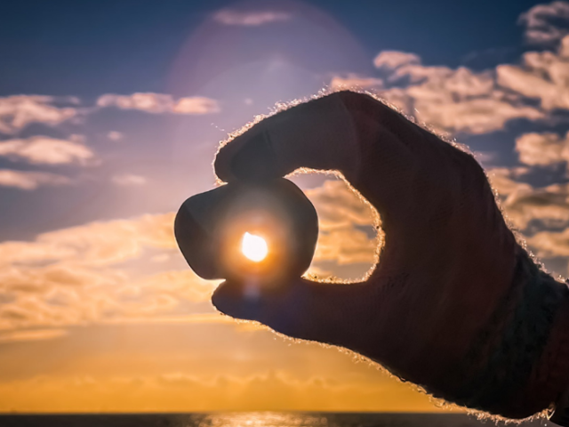 Pebble held up with sunset in the background